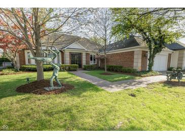 Charming home featuring a lush lawn, brick facade, and artistic bronze statues in the front yard at 411 Sugar Tree Ln, Indianapolis, IN 46260