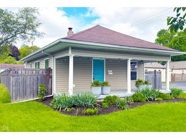 Charming home with a welcoming porch, beautiful landscaping, and a bright blue front door at 6194 Evanston Ave, Indianapolis, IN 46220