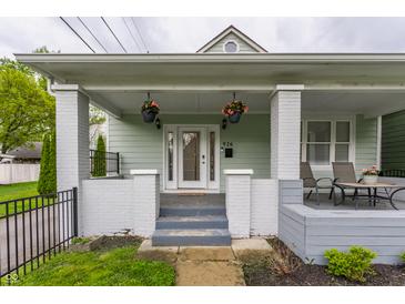 Charming home with a inviting front porch, featuring a cozy seating area and decorative hanging plants at 926 Olive St, Indianapolis, IN 46203