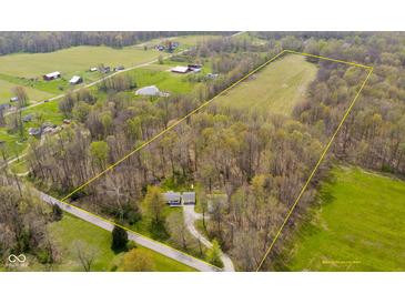Areal view of a home in a wooded and open field setting with a pond and outbuildings in the surrounding area at 9570 S 300 W, Columbus, IN 47201