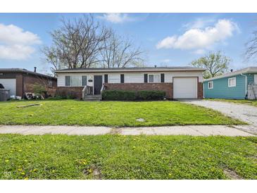 Charming single-story home featuring a brick facade, attached garage and well-maintained front lawn with mature trees at 1819 S Drexel Ave, Indianapolis, IN 46203