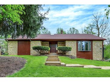 Stone facade home with a brown roof, complemented by manicured green lawn and a wooden pathway at 3875 Arrowhead Ct, Greenfield, IN 46140