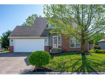 Charming home with a lush green lawn, mature tree, brick accents, and an attached two car garage at 419 Old Glory Dr, Greenfield, IN 46140