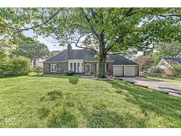 Charming brick home with mature tree, landscaped lawn, and an attached two-car garage at 5747 Allisonville Rd, Indianapolis, IN 46220