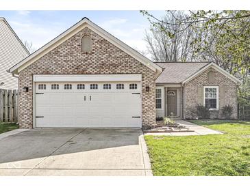 Charming brick home showcasing an attached two-car garage, a welcoming front door, and a well-maintained lawn at 7841 Whitaker Farms Ln, Indianapolis, IN 46237