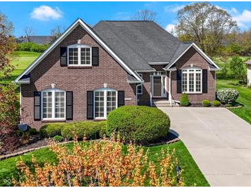 Beautiful brick home featuring manicured landscaping, large windows, and a well-maintained lawn at 10911 Innisbrooke Ln, Fishers, IN 46037