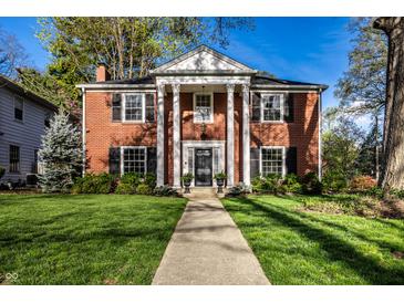Stunning brick home featuring a columned entryway and lush green lawn at 5130 N Washington Blvd, Indianapolis, IN 46205