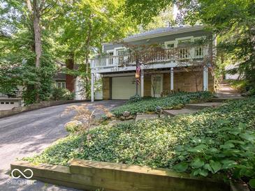 Charming home featuring a lovely front yard, stone facade, and convenient attached garage at 7037 Indian Lake W Blvd, Indianapolis, IN 46236