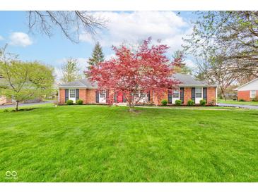 Charming brick home with a lush green lawn and a vibrant red Japanese maple tree in the front yard at 7756 N Audubon Rd, Indianapolis, IN 46250