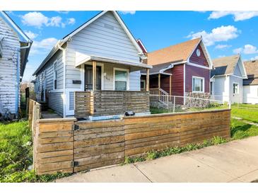 Charming home featuring a quaint covered porch, complemented by a rustic wooden fence, and a well-manicured lawn at 117 W Arizona St, Indianapolis, IN 46225