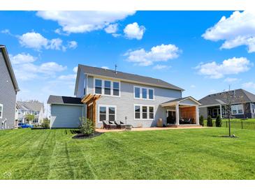 A lovely two-story home with a spacious lawn, patio seating area and beautiful outdoor pergola at 16683 Alex Dr, Noblesville, IN 46060