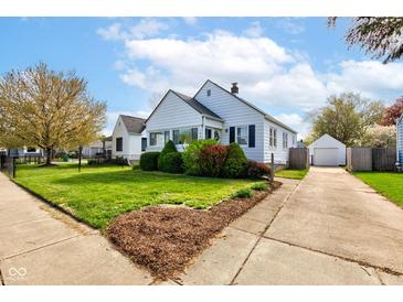 Charming one-story home with green lawn and detached garage on a sunny day at 1865 N Norfolk St, Indianapolis, IN 46224