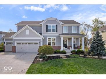 Charming two-story home with a manicured lawn, a three-car garage, and a welcoming front porch with white columns at 957 Commander Ct, Westfield, IN 46074