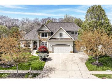 A charming home boasts a stone and brick facade, complemented by a well-manicured lawn and mature trees at 19311 Morrison Way, Noblesville, IN 46060