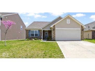 Charming home featuring a well-manicured lawn, brick accents, a two-car garage, and a delightful splash of color from a flowering tree at 2427 Apple Tree Ln, Indianapolis, IN 46229