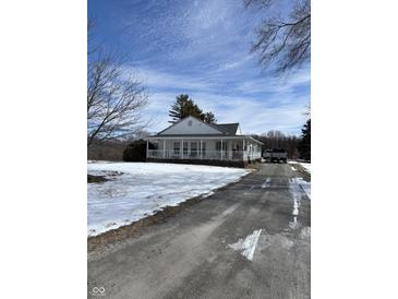 Charming home featuring a covered porch with white railings on a partially snow covered lot at 3333 S Sr 9, Greenfield, IN 46140