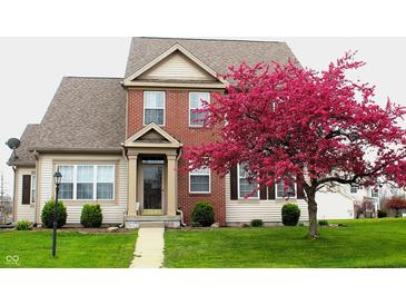 Charming two-story home featuring a brick facade, well-manicured lawn, and a beautiful flowering tree in full bloom at 5266 Hickory Lake Dr, Indianapolis, IN 46235
