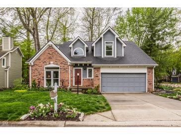 Charming home featuring a brick facade, a gray roof, an attached garage and a well-manicured front lawn at 5467 Winterhazel Dr, Indianapolis, IN 46254