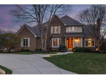 Charming two-story brick home with a well-manicured lawn, mature trees, and a concrete driveway at 12715 Norfolk Ln, Carmel, IN 46032