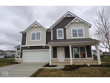 Two-story home features a two car garage, dark brown siding and cream colored accents under a cloudy sky at 17039 Silo Ridge Way, Noblesville, IN 46060