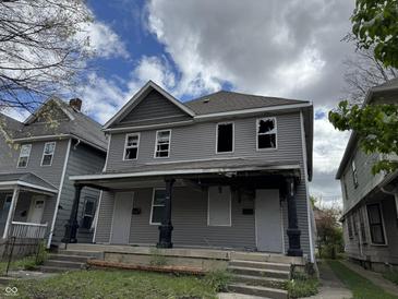 Two-story duplex with gray siding, broken windows, and a shared front porch, needs renovation at 433 Jefferson Ave, Indianapolis, IN 46201