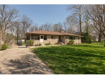 Charming single-story home with a stone facade, mature trees, and a well-maintained lawn at 614 Debra Ln, Indianapolis, IN 46217