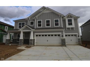 A two-story home with gray siding, stone accents, a two-car garage and a concrete driveway at 12417 Fresh Stock Dr, Noblesville, IN 46060