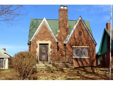 Charming brick home with green roof and detailed ironwork on the front door at 3208 Brookside Pkwy N Dr, Indianapolis, IN 46218