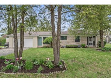 Charming stone home featuring a lush, green lawn and a beautiful garden bed at 3818 Kessler Boulevard East Dr, Indianapolis, IN 46220