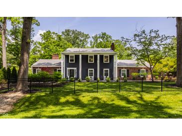 Charming two-story home with a manicured lawn and a classic black fence at 654 E 79Th St, Indianapolis, IN 46240