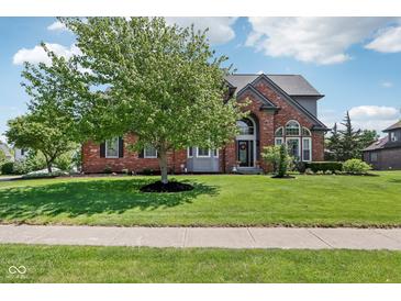 Charming brick home featuring a landscaped yard and mature tree, showcasing curb appeal at 7323 Elm Ridge Dr, Indianapolis, IN 46236