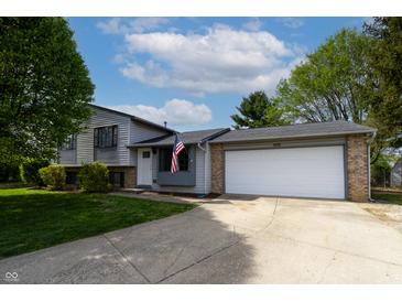 Charming home featuring a two-car garage, well-manicured lawn and patriotic American flag at 8232 N Chaucer Ct, Columbus, IN 47201