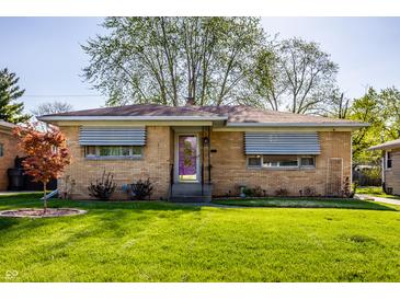 Charming brick home featuring a well-maintained lawn and a distinctive purple front door at 1031 N Lesley Ave, Indianapolis, IN 46219