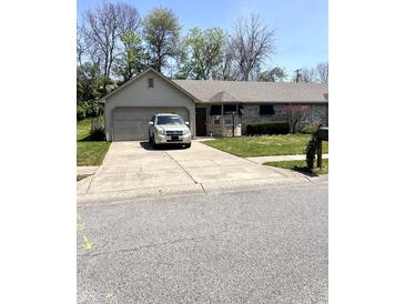 Charming single-story home features a gray brick exterior, well-maintained lawn and a long driveway at 4211 Medina Way, Indianapolis, IN 46227