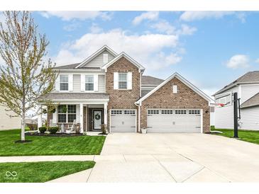 Charming two-story brick home featuring a three-car garage, well-manicured lawn, and inviting front porch at 6040 Juniper Ct, Whitestown, IN 46075