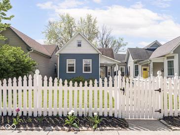 Charming home features a blue exterior, white picket fence, and well-manicured lawn, enhancing its curb appeal at 1429 Fletcher Ave, Indianapolis, IN 46203