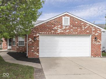 Two car garage featuring red brick exterior, black mulch landscaping and concrete driveway at 212 Westridge Blvd, Greenwood, IN 46142