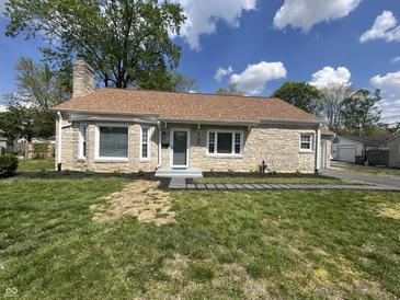 Charming stone cottage with a neatly landscaped front yard under a bright, partly cloudy sky at 2135 Union St, Columbus, IN 47201
