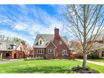 Charming brick Tudor-style home with a well-manicured lawn and blossoming trees at 5611 N Delaware St, Indianapolis, IN 46220