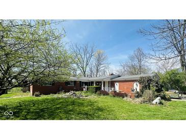 Charming single-story brick home with a well-manicured lawn and a covered front porch and beautiful blue skies at 6622 Stanley Rd, Camby, IN 46113