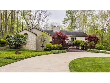 Charming stone home featuring lush landscaping, a curved driveway, and a spacious front deck for outdoor enjoyment at 8901 Shetland Ln, Indianapolis, IN 46278