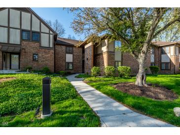 Brick condominium exterior featuring a walkway, green space, mature tree, and manicured landscaping at 2141 Rome Dr # Apt B, Indianapolis, IN 46228
