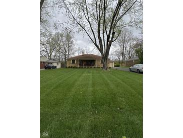 Charming brick home features a covered front porch and a beautifully manicured lawn, perfect for outdoor enjoyment at 5774 N Ewing St, Indianapolis, IN 46220