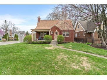 Charming brick home featuring a well-maintained lawn and inviting front porch at 5697 Broadway St, Indianapolis, IN 46220
