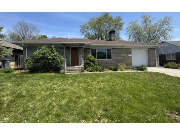 Charming brick ranch-style home with attached garage, lush lawn, and beautiful landscaping at 1021 N Bolton Ave, Indianapolis, IN 46219