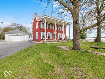 Exterior view of the residence showcasing the classic red brick, white columns, and spacious front yard at 1394 N Michigan Rd, Shelbyville, IN 46176