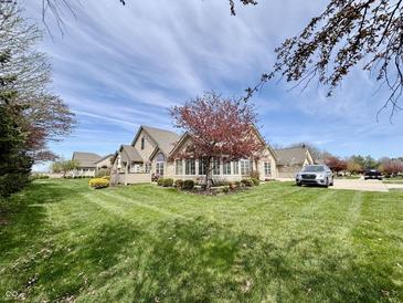 Inviting home featuring a lush green lawn, a blooming tree, and a long driveway at 16924 Maple Springs Way, Westfield, IN 46074