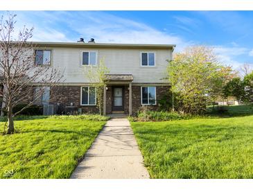 Charming townhome features a brick facade, well-manicured lawn, and inviting walkway leading to the front door at 6026 Oakbrook Ln, Indianapolis, IN 46254