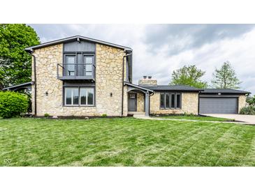 Charming stone house featuring a second-story balcony, well-manicured lawn, and an attached two-car garage at 660 Sun Valley Ct, Indianapolis, IN 46217
