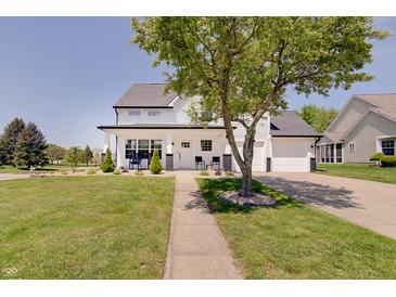 Charming two-story white home featuring a well-manicured lawn and inviting covered front porch with black accents at 11124 Winterwood Dr, Indianapolis, IN 46235